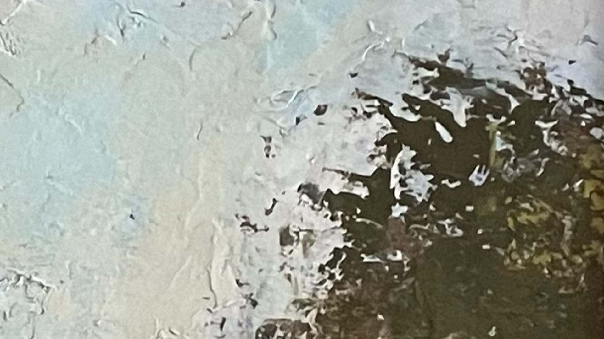 Close-up of peeling paint or ice with dark patches